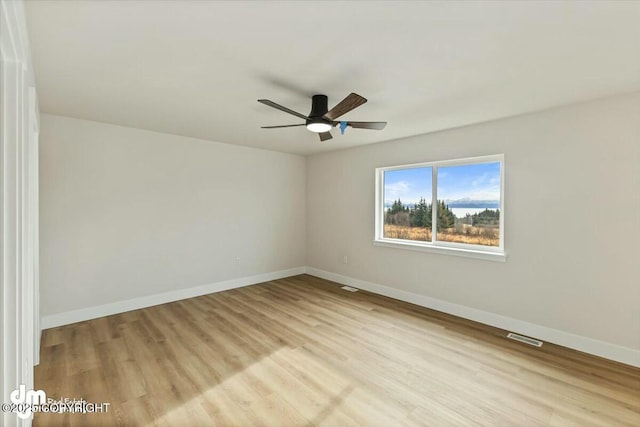 unfurnished room with visible vents, ceiling fan, light wood-style floors, and baseboards