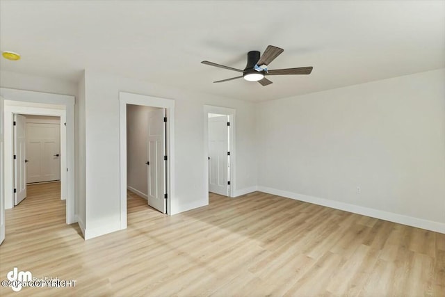 unfurnished bedroom with baseboards, light wood-style floors, ceiling fan, and a spacious closet