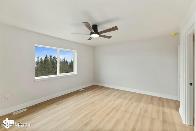 spare room with ceiling fan, baseboards, visible vents, and light wood-type flooring