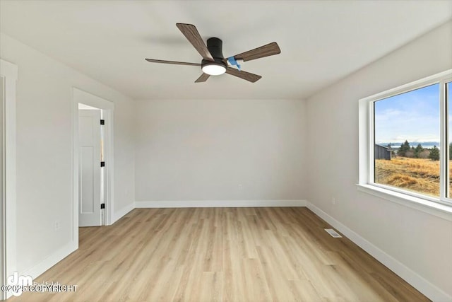 empty room featuring light wood finished floors, a ceiling fan, and baseboards