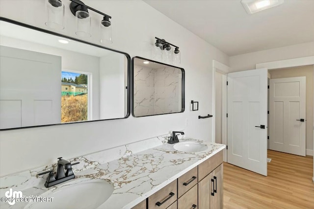 full bathroom with double vanity, wood finished floors, and a sink