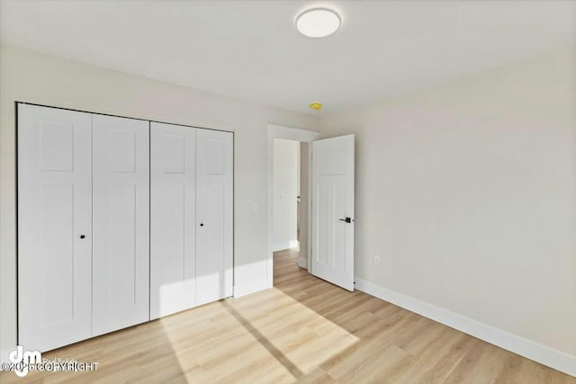 unfurnished bedroom with light wood-type flooring, baseboards, and a closet