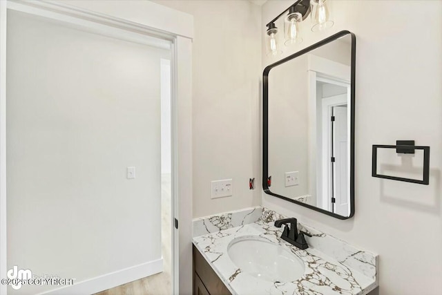 bathroom featuring baseboards, wood finished floors, and vanity