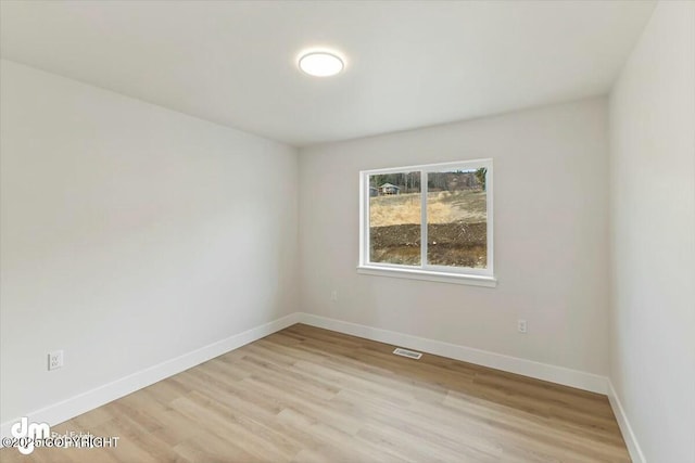 empty room with light wood-style floors, baseboards, and visible vents