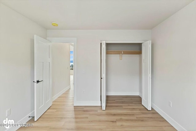 unfurnished bedroom with light wood-style flooring, baseboards, and a closet