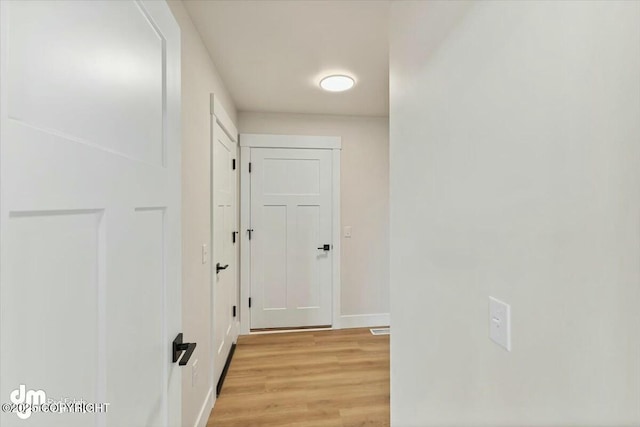 hall featuring visible vents, baseboards, and light wood-style floors