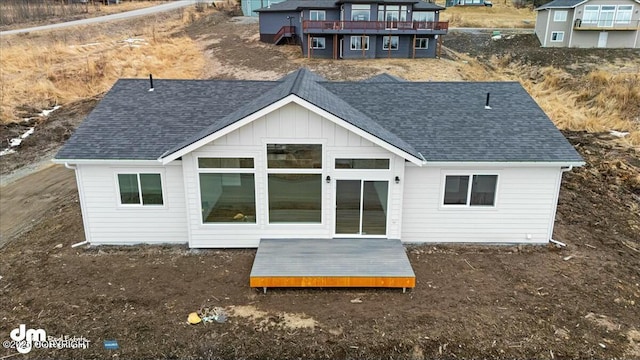 back of house featuring a deck, board and batten siding, and a shingled roof