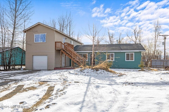 chalet / cabin with an attached garage, stairs, and fence