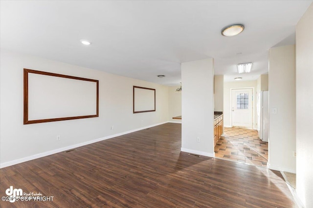 empty room featuring wood finished floors, visible vents, and baseboards