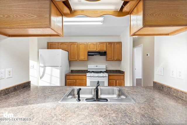 kitchen with under cabinet range hood, white appliances, a sink, brown cabinetry, and dark countertops