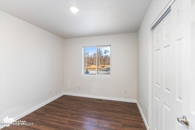 unfurnished bedroom with visible vents, a closet, baseboards, and dark wood-style flooring