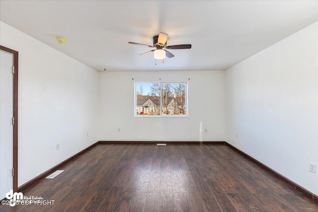 empty room with visible vents, wood finished floors, a ceiling fan, and baseboards