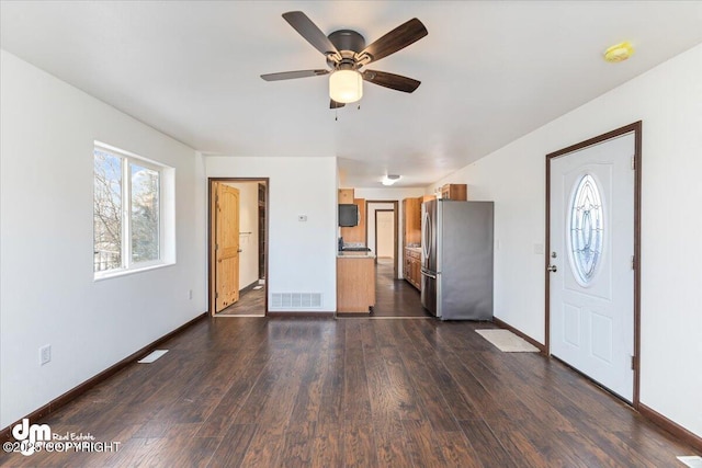 interior space featuring baseboards, visible vents, dark wood finished floors, and a ceiling fan