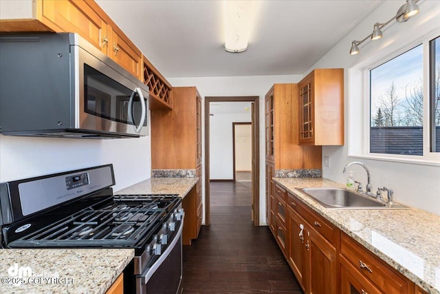 kitchen with stainless steel appliances, brown cabinets, a sink, and dark wood-style floors