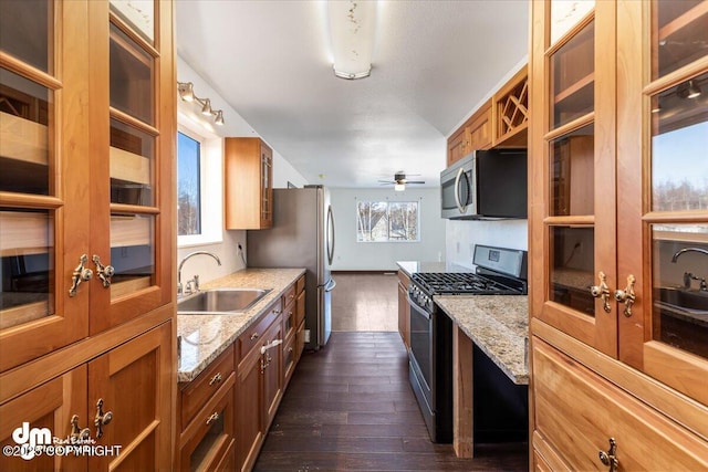 kitchen featuring stainless steel appliances, brown cabinets, dark wood-type flooring, and a sink