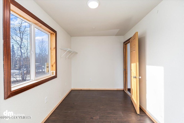 corridor with dark wood-style floors, a wealth of natural light, and baseboards