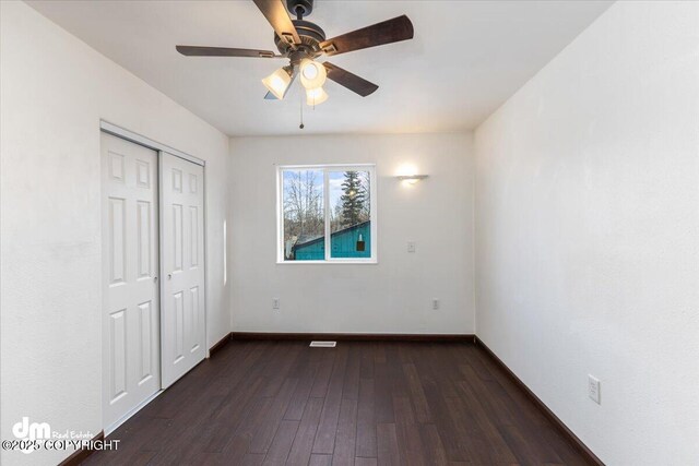 unfurnished bedroom with a ceiling fan, a closet, dark wood finished floors, and baseboards