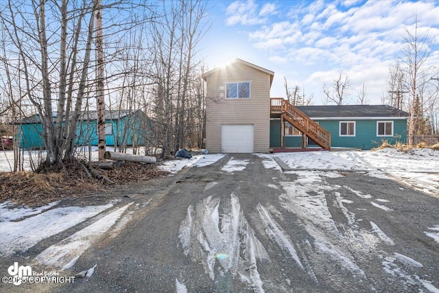 view of front of property with a garage, driveway, and stairway