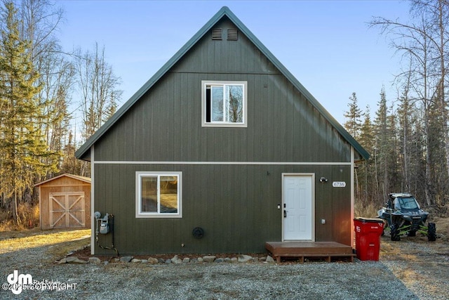 back of house with an outdoor structure and a shed