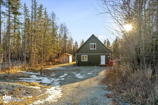 view of home's exterior with a storage unit, an outbuilding, and gravel driveway