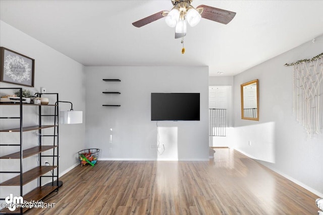 unfurnished living room with baseboards, wood finished floors, and a ceiling fan