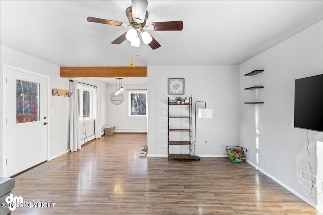 unfurnished living room with a ceiling fan, wood finished floors, and baseboards