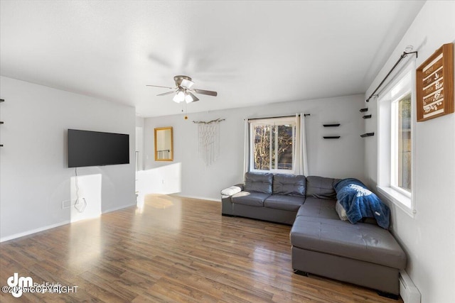 living area featuring ceiling fan, a baseboard radiator, baseboards, and wood finished floors