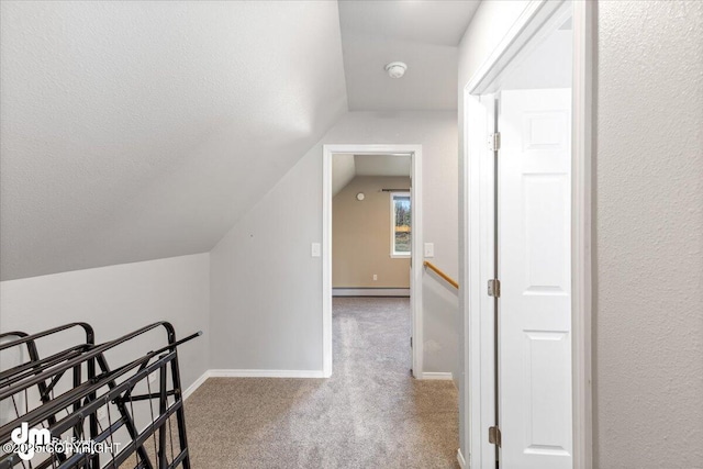 corridor with baseboard heating, baseboards, carpet, and vaulted ceiling