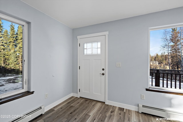 entryway featuring baseboard heating, baseboards, and wood finished floors