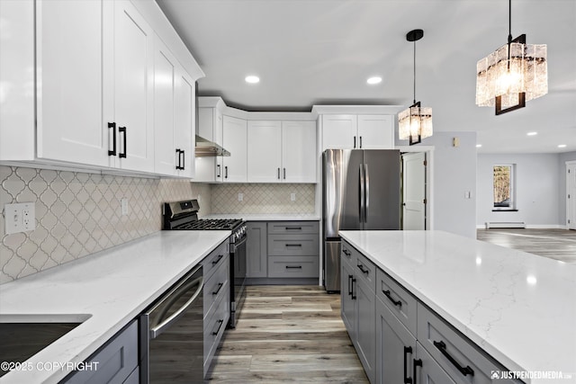 kitchen with light stone counters, gray cabinetry, stainless steel appliances, and a baseboard radiator