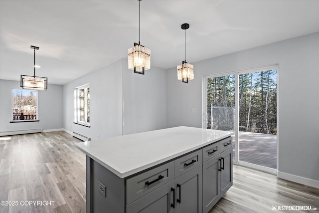 kitchen featuring light wood finished floors, a kitchen island, gray cabinets, a baseboard heating unit, and baseboard heating