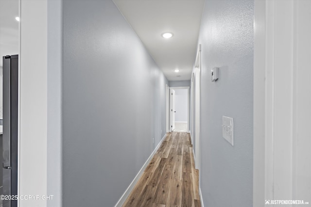 corridor featuring baseboards and wood finished floors