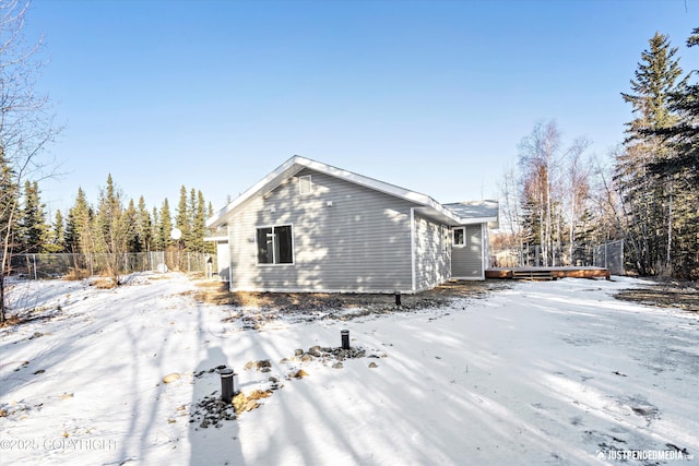 view of snowy exterior featuring a wooden deck and fence