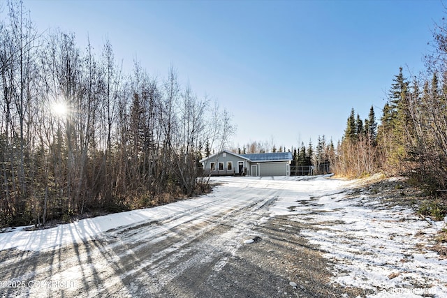 view of road with a wooded view and driveway