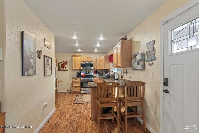 35376 Betty Lou Dr, Sterling, AK 99672 - kitchen featuring dark countertops, a breakfast bar, a peninsula, appliances with stainless steel finishes, and light wood-style floors