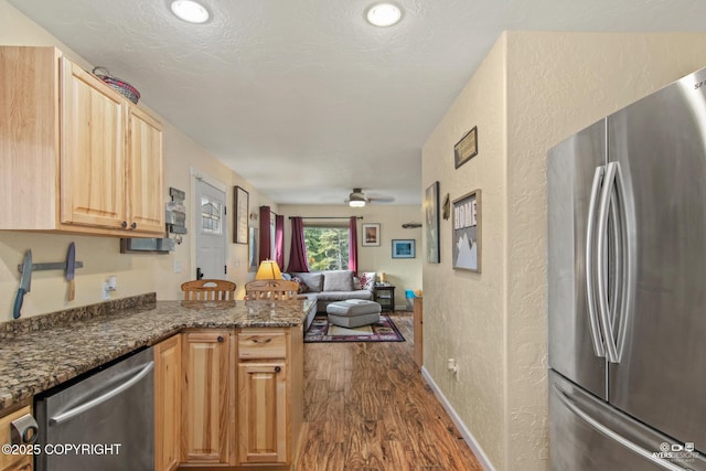 35376 Betty Lou Dr, Sterling, AK 99672 - kitchen with dark wood finished floors, open floor plan, a peninsula, a textured wall, and stainless steel appliances