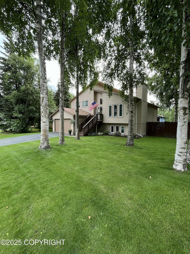 exterior space with a garage, driveway, a front lawn, and fence