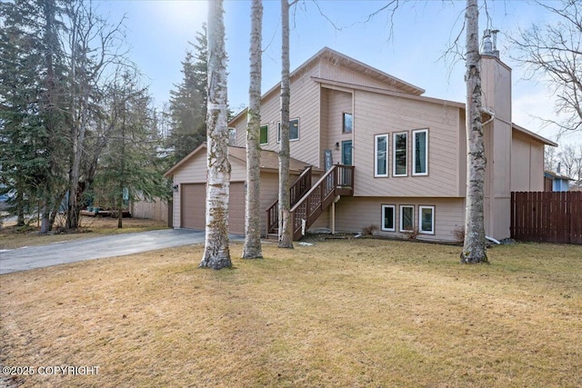 exterior space featuring fence, stairway, a lawn, a garage, and driveway