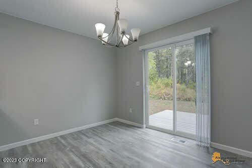 spare room featuring a chandelier, baseboards, and wood finished floors