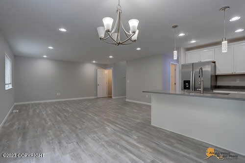 kitchen with white cabinets, pendant lighting, light wood-style floors, and stainless steel refrigerator with ice dispenser