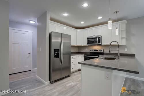 kitchen with white cabinetry, a peninsula, appliances with stainless steel finishes, and a sink