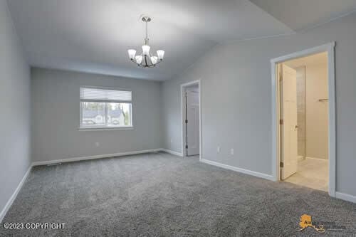 unfurnished room with vaulted ceiling, baseboards, carpet floors, and a chandelier