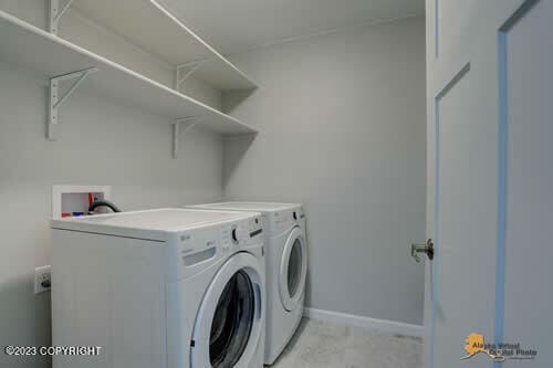 clothes washing area featuring baseboards, washing machine and dryer, and laundry area