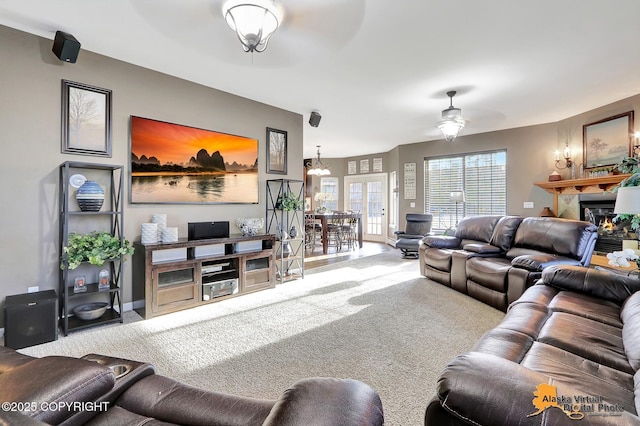 carpeted living room with a warm lit fireplace and ceiling fan