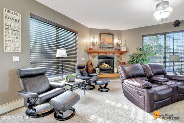 living area with a baseboard heating unit, baseboards, and a glass covered fireplace