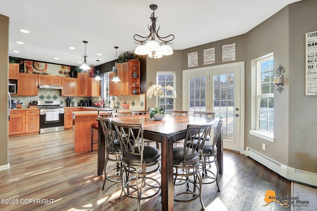 dining room featuring a baseboard heating unit, baseboards, light wood-type flooring, recessed lighting, and a notable chandelier