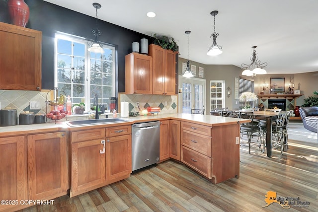 kitchen featuring open floor plan, dishwasher, light countertops, a peninsula, and a sink