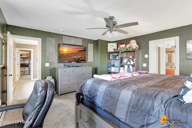 bedroom featuring connected bathroom, light colored carpet, and ceiling fan