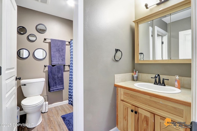 full bathroom with toilet, wood finished floors, a shower with shower curtain, baseboards, and vanity