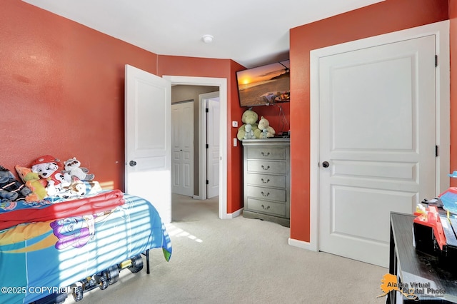 bedroom with light colored carpet and baseboards